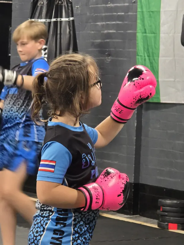 Young girl in pink gloves punching during a kids Muay Thai class at Pride Gym Sheffield