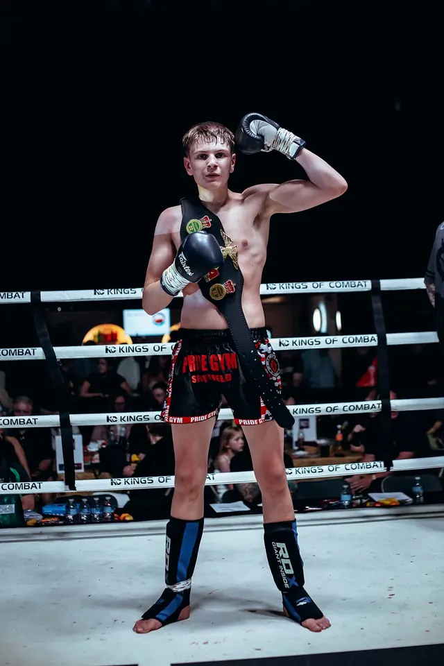 Young Pride Gym kickboxer in Pride Gym Sheffield shorts wearing a championship belt at Kings of Combat